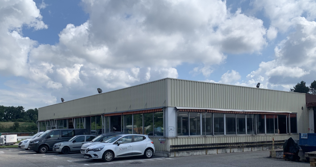 L’atelier des Camarines : un des nombreux bâtiments de l’ADTP en Haute-Savoie. Celui-ci abrite un ESAT spécialisé dans la numérisation, le mailing, l’assemblage et le conditionnement. Son toit en fait une proie facile de la précarité thermique d’été.